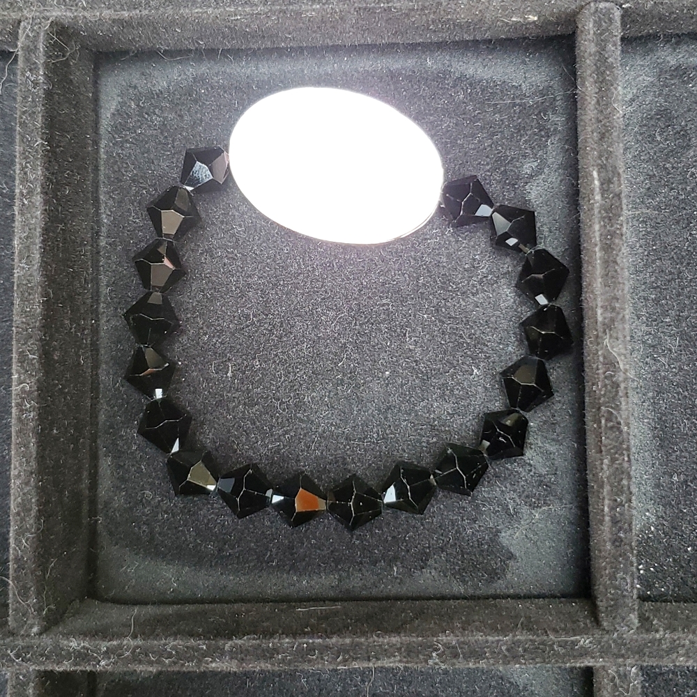 Bracelet with black beads and oval pendant that is reversible.